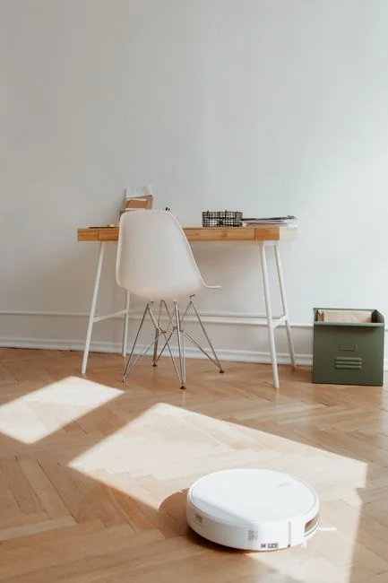 A woman carefully wraps a sofa in protective material while packing boxes in a bright room.